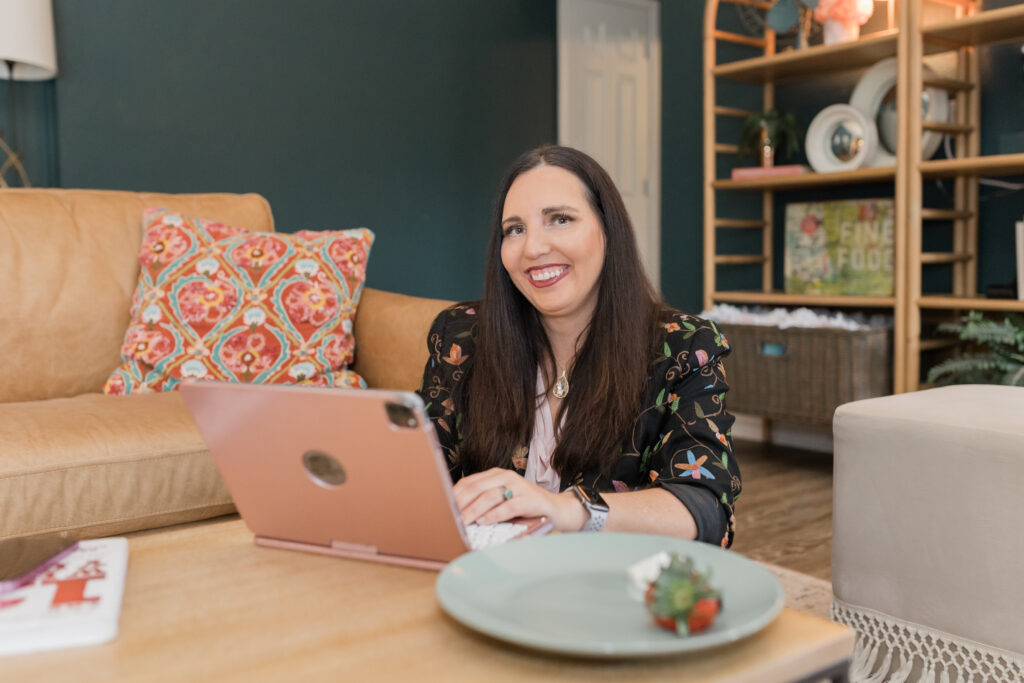 Christina Rose smiling while working on her laptop, offering ADHD family coaching, ADHD home organization tips, and ADHD systems for families from Oklahoma.